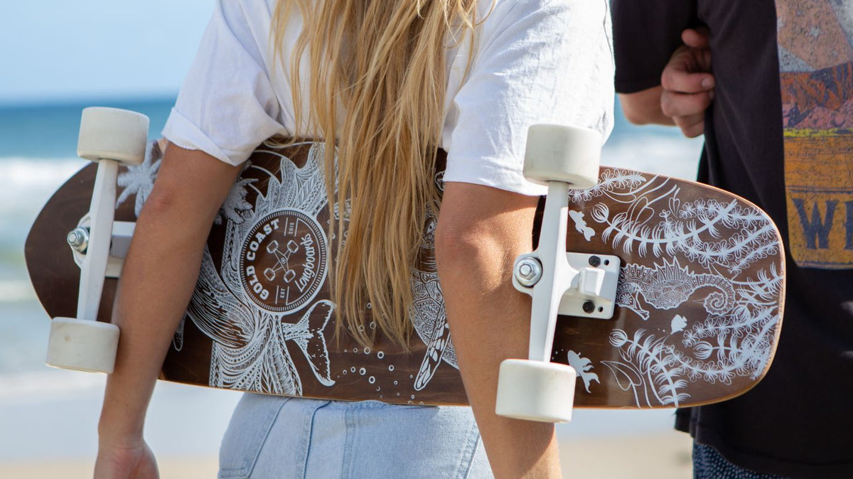Two people holding GCLB boards with the deck artwork, trucks and wheels visible.