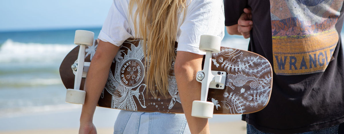Two people holding GCLB boards with the deck artwork, trucks and wheels visible.